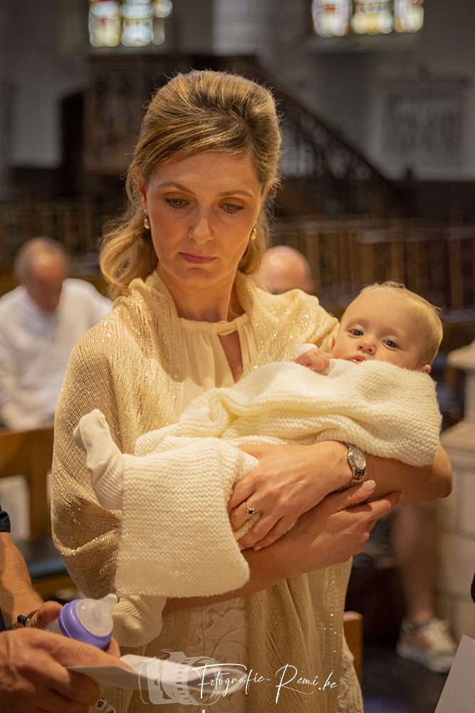 Vrouw houdt een in een deken gewikkelde baby vast tijdens een doopceremonie in de kerk.
