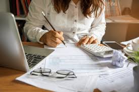 Persoon berekent de kosten voor een budgetmeterhuwelijk, schrijft op papier met rekenmachine en laptop.