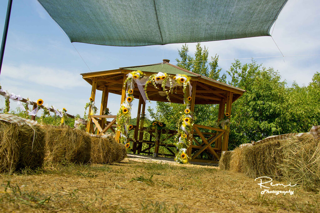 Rustiek bruidsprieel versierd met zonnebloemen, perfect voor een zomerbruiloft in de buitenlucht.