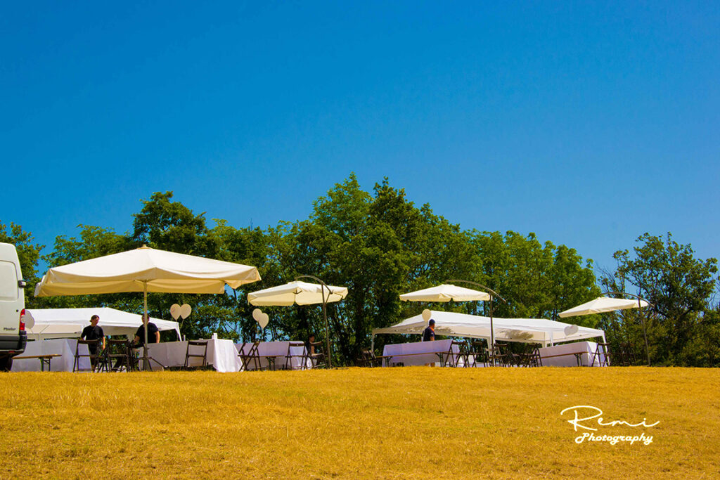 Buitenopstelling met witte tenten, tafels en parasols op een zonnige dag. Perfect voor een zomerfeest.