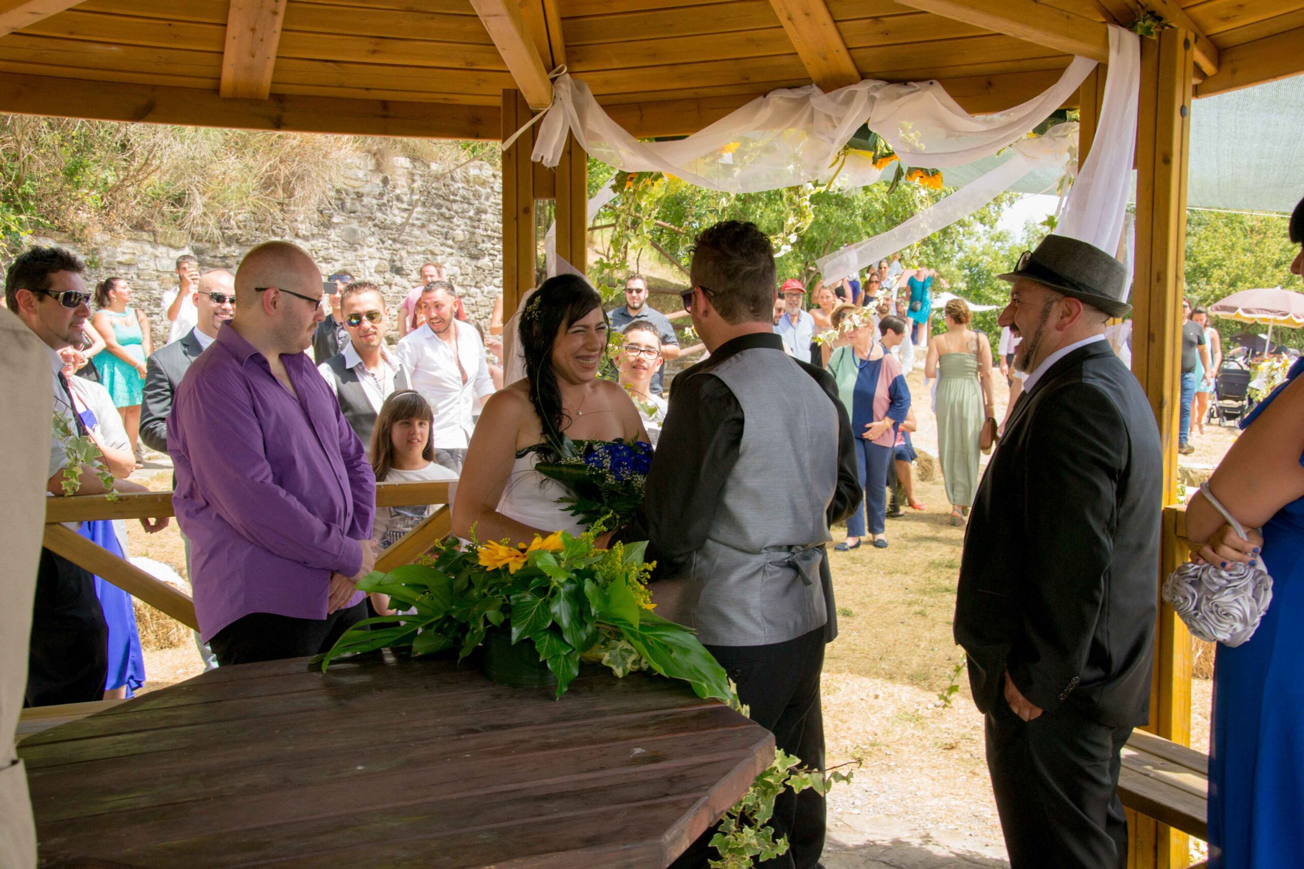 Bruid en bruidegom tijdens huwelijksceremonie in de buitenlucht met gasten