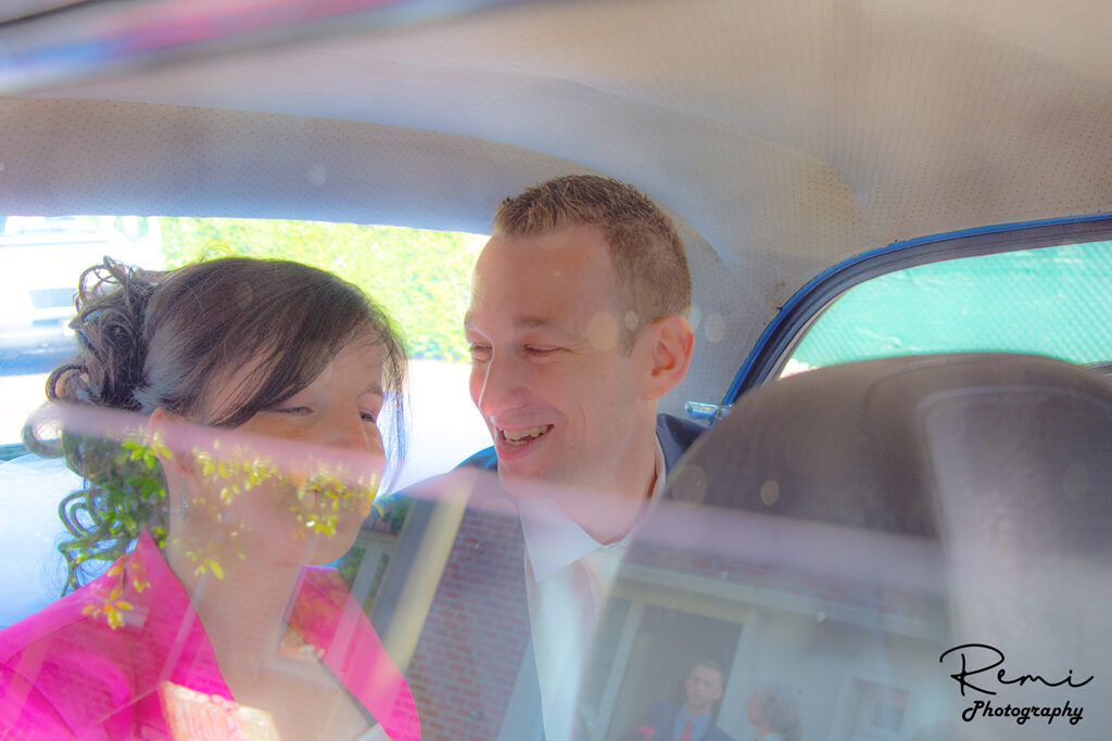 Jonggehuwden lachend in een auto na hun huwelijk in Niel.