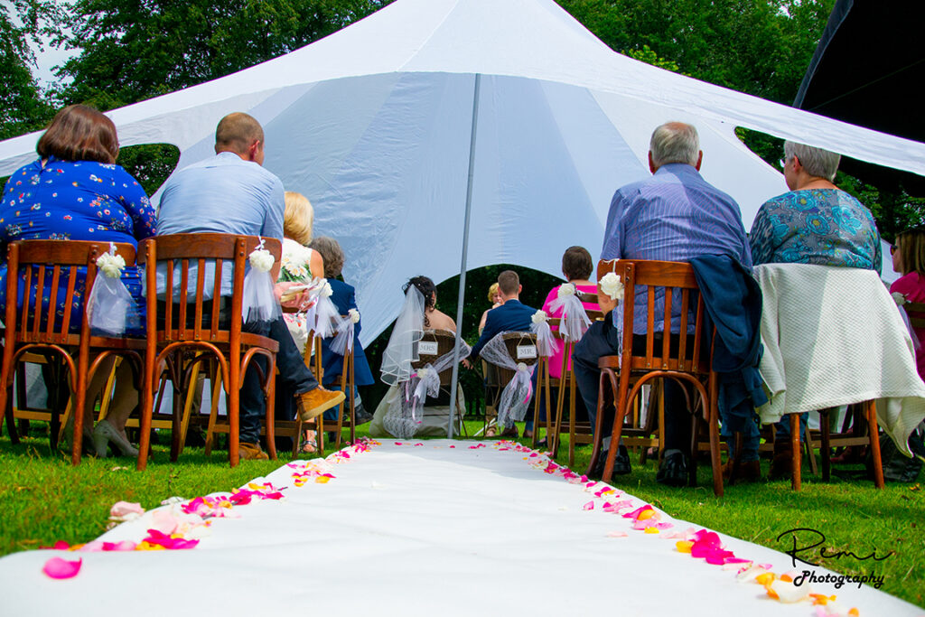 Huwelijksceremonie in Niel met bruid, bruidegom en gasten onder een witte tent.