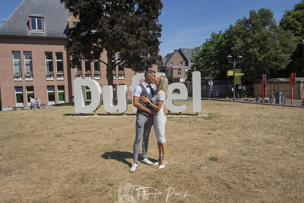 Zoenend bruidspaar voor het bord "Duffel", vastgelegd tijdens een 2-daagse-huwelijksreportage.