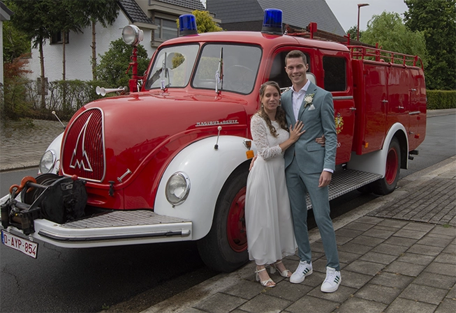 Jonggehuwden poseren met vintage brandweerwagen; huwelijksfotograaf Lint.