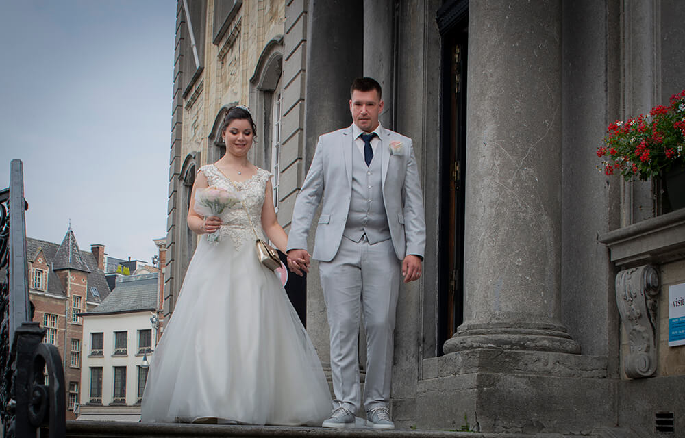 Bruid en bruidegom verlaten gebouw na huwelijk in Lier.