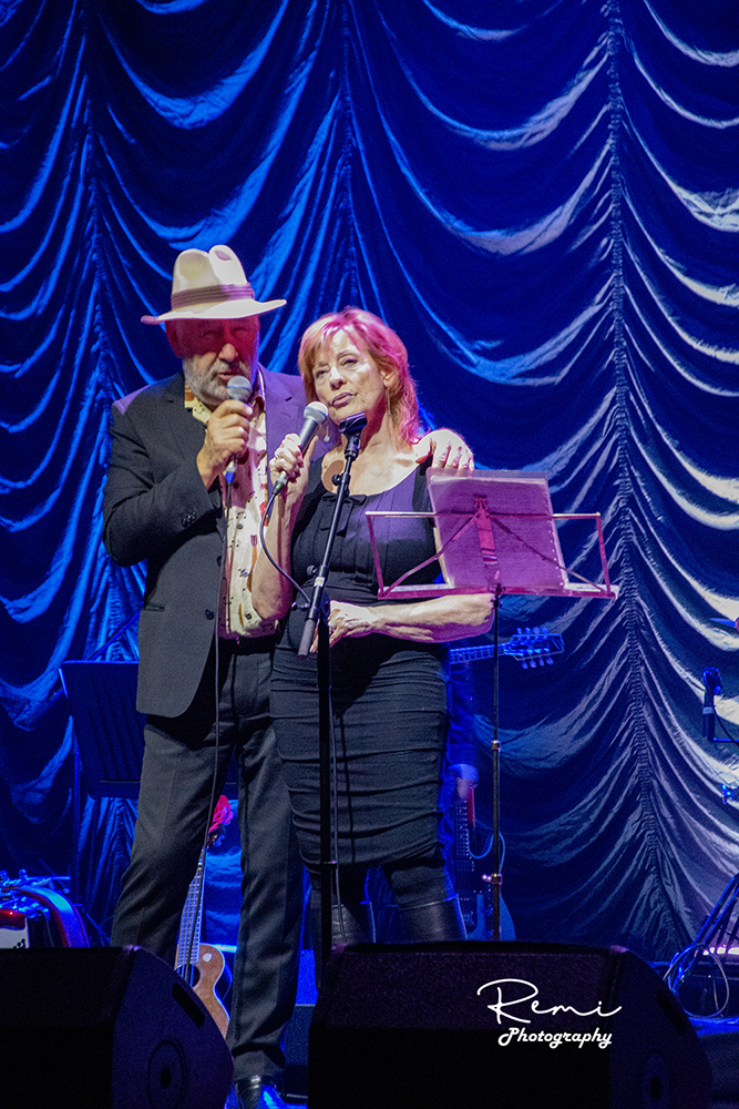 Twee zangers treden op het podium op met microfoons tijdens een concert.