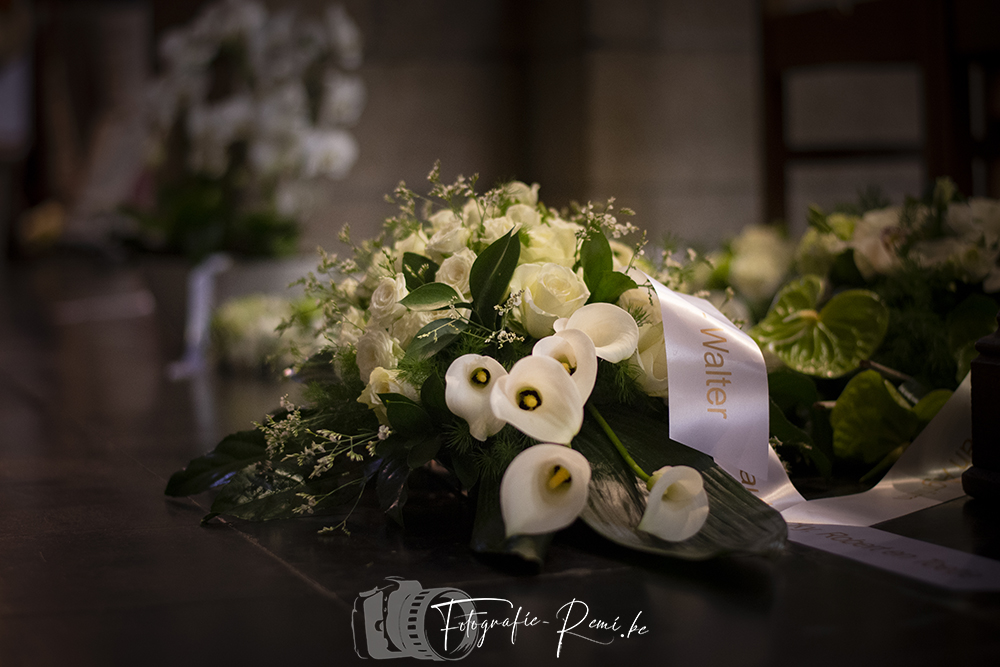 Rouwbloemen met witte rozen en calla's met een lint met de tekst "Walter