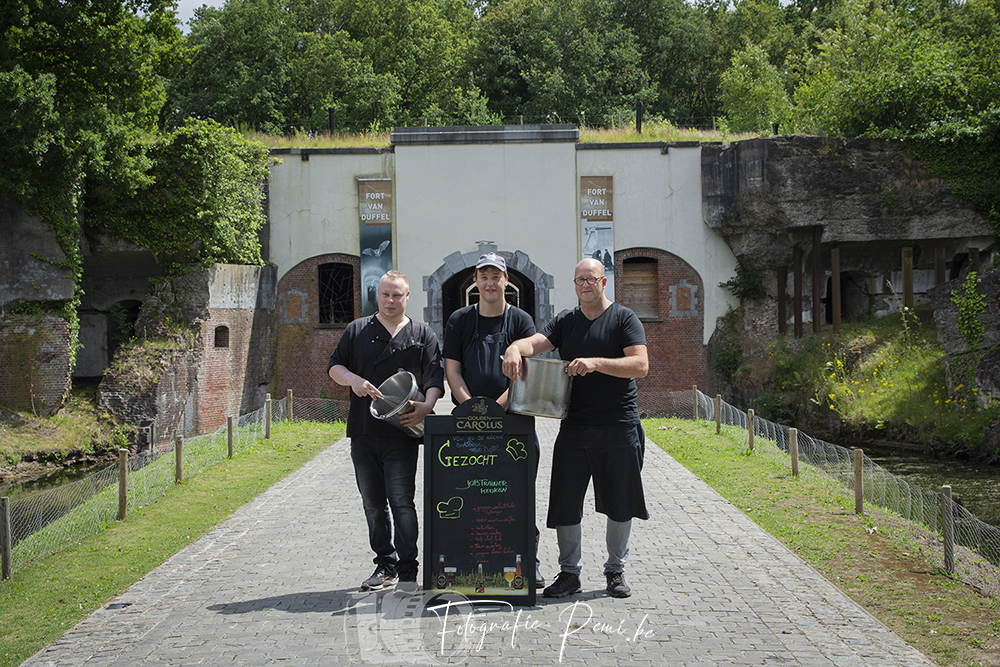 Gouden Carolus restaurantpersoneel bij Fort van Duffel met bord "GEZOCHT".