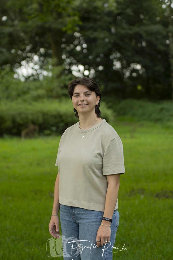 Lachende vrouw in een buitenportret, waarbij ze gebruikmaakt van natuurlijk licht. Ze poseert voor een portretfoto.