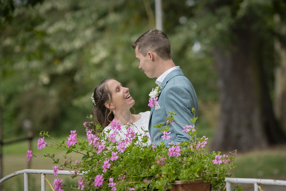Het pasgetrouwde stel kijkt elkaar aan op hun trouwdag, omringd door roze bloemen.
