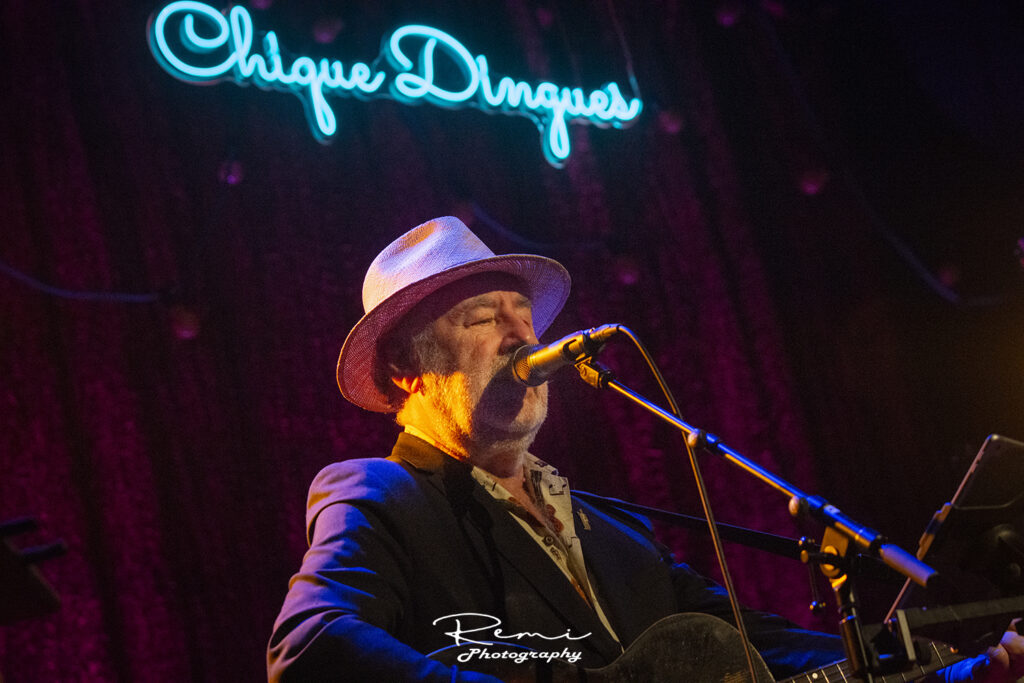 Zangeres treedt op bij livemuzieklocatie Chique Dingues onder een neonreclame.